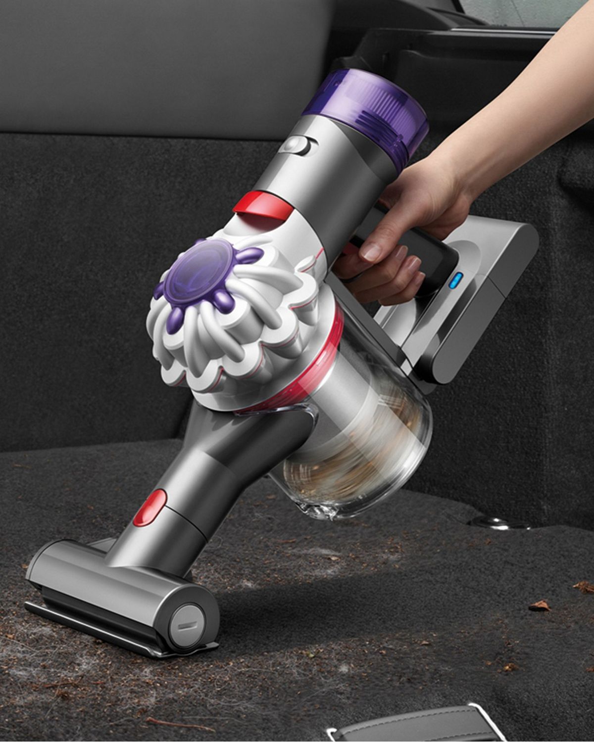 The Dyson Car+Boat handheld vacuum with the Mini motorised tool cleaning dirt inside of a car.